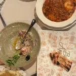 Traditionelles bulgarisches Essen in Bansko mit verschiedenen Gerichten, darunter Chomlek und Salat, angerichtet auf einem gedeckten Tisch mit Beilagen und Brot.