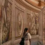 Frau läuft entlang von Wandgemälden in der Kuppel des Petersdoms