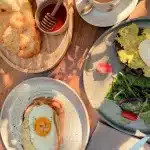 Frühstück in Albanien – traditionelles Petulla mit Honig, Avocado-Toast und Spiegelei auf Brot.