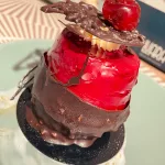 Fein dekoriertes Dessert in einem albanischen Café, verziert mit Schokolade und einer Kirsche.