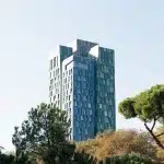 Moderne Architektur in Tirana, Albanien, mit einem markanten Hochhaus, das zwischen Bäumen hervorragt.