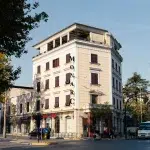 Historisches Gebäude „Monarc“: Ein charmantes, mehrstöckiges Gebäude mit weißer Fassade und dunklen Fensterläden. Der Schriftzug „Monarc“ prangt an der Ecke des Hauses.