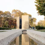 Ein modernes Denkmal mit reflektierenden Oberflächen, umgeben von herbstlichem Flair im Herzen von Blloku.