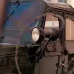 Detailaufnahme eines historischen Militärfahrzeugs vor Bunk'Art 2, durch einen Stacheldrahtzaun eingefangen.