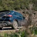 Ein robuster blauer Mietwagen (Ford Kuga) steht auf einer Schotterstraße inmitten einer hügeligen Landschaft – ein Symbol für Abenteuer und Vielseitigkeit.