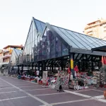 Die moderne Architektur des Pazari i Ri, eingerahmt von den lebhaften Marktständen und den umliegenden Wohnhäusern.