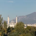 Panoramablick auf die Große Moschee von Tirana, eingebettet in üppiges Grün mit dem Berg Dajti im Hintergrund.