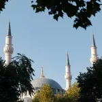 Die eleganten Minarette der Großen Moschee von Tirana, die stolz hinter dichten Baumkronen emporragen.