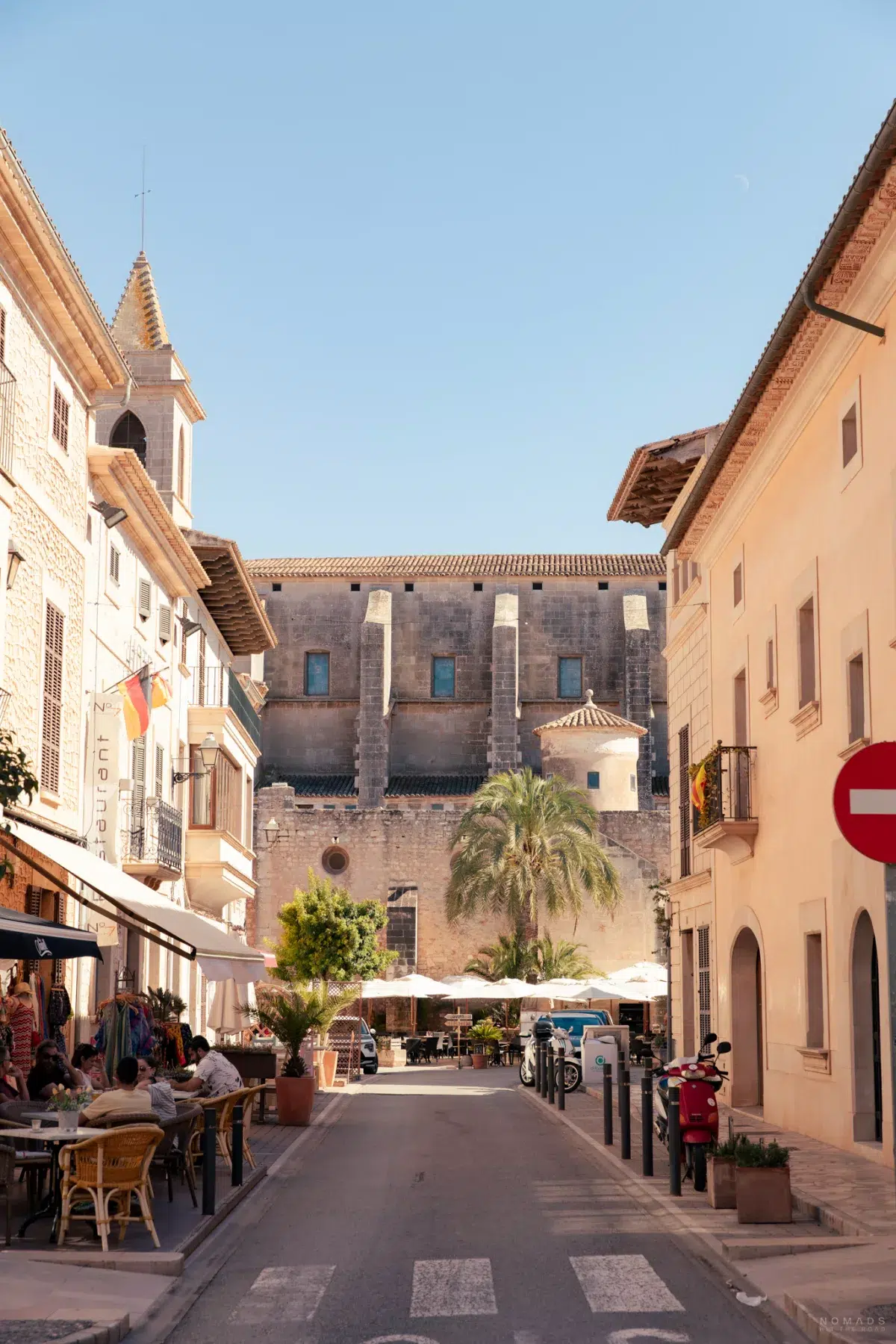 Straße mit Blick auf die Fassade der Kirche Sant Andreu de Santanyí und einem Restaurant an der Seite
