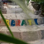 Bunte, handgemalte Schriftzüge „I ❤ Berat“ auf einer Treppenstufe in Berat, Albanien, zwischen Pflanzen und Blumen.