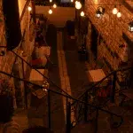 Ein gemütlicher Innenhof eines Restaurants in Berat, Albanien, beleuchtet von warmen Lichterketten, mit Sitzgelegenheiten und Blumen.
