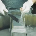 Messer wird geschärft auf einem Stein und über Wasser in einem Messerladen in Asakusa
