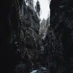 Blick entlang der schmalen Schlucht der Partnachklamm mit hoch aufragenden Felswänden und dem darunter fließenden Wasser.