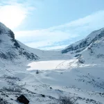 Blick auf den schneebedeckten Athabasca Glacier umgeben von Bergen und einem Tal aus Schnee