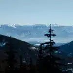 Blick durch die Bäume auf die majestätischen Berge. Ein Highlight der Schneemobil-Tour: Natur pur und weite Ausblicke.