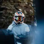 Person mit Helm und Skibrille auf einem Schneemobil.