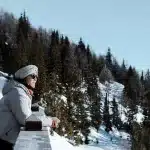 Frau genießt die Aussicht von der Berghütte. Nach dem Adrenalin-Kick auf dem Schneemobil ist dies der perfekte Ort zum Entspannen.
