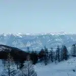 Weitläufiger Blick über das Tal und die schneebedeckten Gipfel der kanadischen Rocky Mountains. Die Schneemobil-Strecke führt bis knapp unter den Gipfel mit atemberaubender Aussicht.