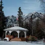 Runde Pagode mit Kanada Flagge auf dem Dach steht in einem Park vor einer Bergkulisse