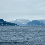 Blick auf eine weite Wasserfläche mit schneebedeckten Bergen im Hintergrund, typisch für die raue Küstenlandschaft von Vancouver Island und British Columbia.