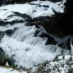 Wasserfall in den Sooke Potholes, umgeben von schneebedeckten Felsen.