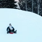 Zwei Personen beim fröhlichen Schlittenfahren auf einer verschneiten Rodelbahn in Whistler.