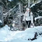Frau mit Winterkleidung und Rucksack wandert durch den verschneiten Wald auf einem Winterwanderweg in Whistler.