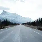 Blick auf die Straße des David Thompson Highways mit Bergen im Hintergrund