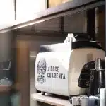 Detail einer Siebträgermaschine im Café El Doce Cuarenta – mit mexikanischem Totenkopf-Design und Sonnenlicht im modernen Interieur.