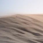 Feiner Wüstensand weht über eine Düne – ruhiger Moment in der kargen, windigen Landschaft von El Mogote.
