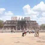 Menschen laufen vor dem Templo de los Guerreros, der etliche Säulen davor hat