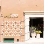 Farbige Fassade des Cafés Santa Hierba mit Mosaikfließen als Deko an der Wand und Kakteen im Fenster