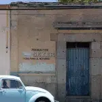 blauer VW Käfer vor einem Haus