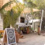 Friseur in einem umgebauten Bus unter Bäumen und einem Sonnensegel