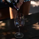 Frau gießt Rotwein in ein Weinglas