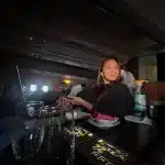 Frau in der Business Class mit Wasserflasche, Getränken und modernen Bedienfeldern.