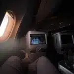 Blick auf einen Passagier, der einen Film in der Business Class sieht, mit Blick aus dem Fenster und Sonnenlicht.