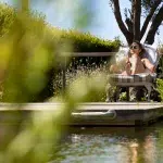 Naturpool und Liege mit einer Frau, die ihr Amex Platinum Hotel Upgrade in einer luxuriösen Hotelanlage genießt.