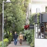 Zwei Männer laufen auf einem Bürgersteig, der gesäumt ist von Restaurants und Bäumen
