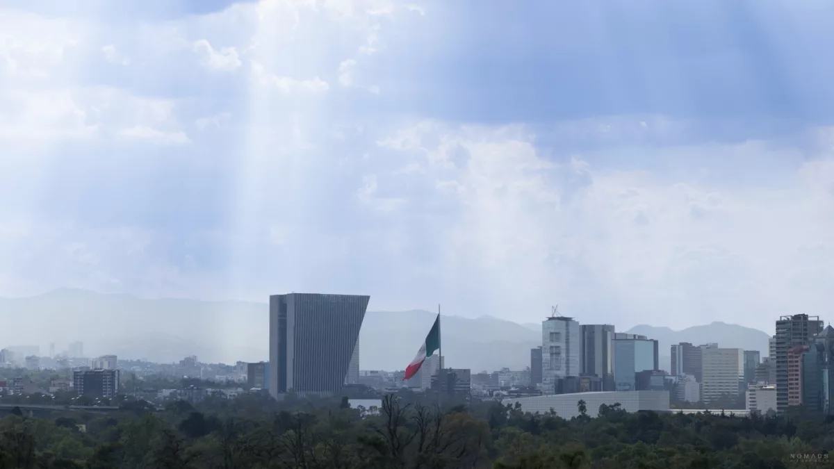 Ausblick vom Castillo de Chapultepec auf Mexiko-Stadt mit Nationalflagge und moderner Skyline im Hintergrund.