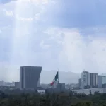 Ausblick vom Castillo de Chapultepec auf Mexiko-Stadt mit Nationalflagge und moderner Skyline im Hintergrund.