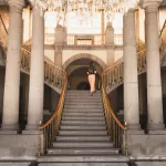 Eingangshalle im Castillo de Chapultepec mit prunkvoller Doppeltreppe und klassischer Säulenarchitektur.