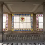 Panoramafenster mit bunten Glasmalereien und mexikanischem Nationalemblem im Castillo de Chapultepec.