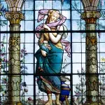 Detailreiche Glasmalerei im Castillo de Chapultepec, die eine historische Frauenfigur mit Blumen und klassischen Säulen zeigt.