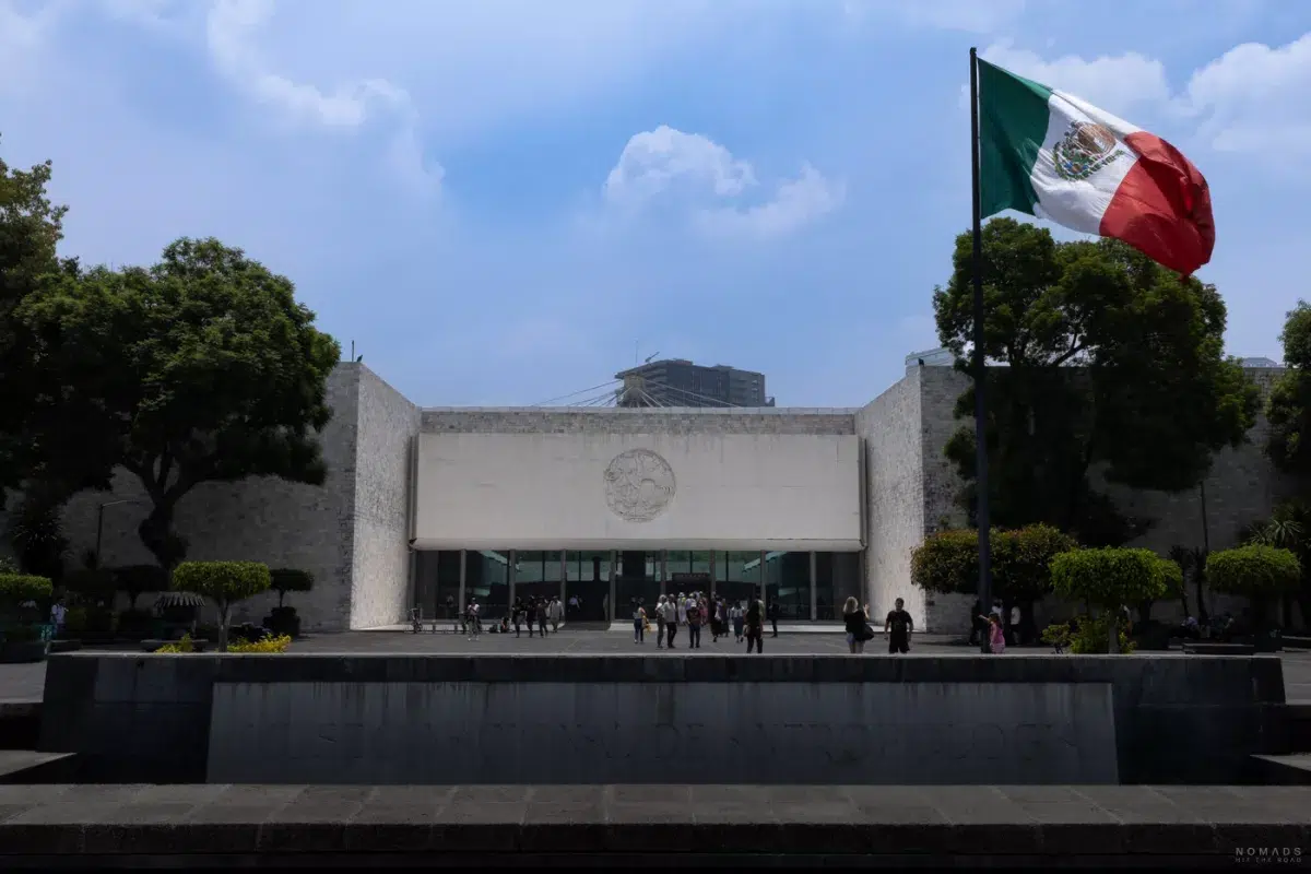 Monumentales Eingangsportal des Museo Nacional de Antropología in Mexiko-Stadt mit großer mexikanischer Flagge.