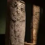 Relief-Stele mit feinen Schnitzereien im Halbdunkel des Museums.