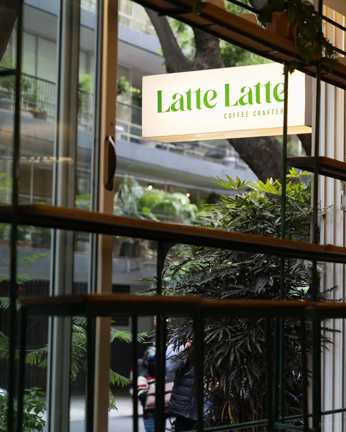 Innenansicht des Cafés Latte Latte in Polanco, Mexiko City – mit beleuchtetem Schild und Blick auf moderne Gebäude im Hintergrund