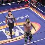 Lucha-Libre-Kämpfer mit Maske und Glitzerstiefeln im Ring der Arena Coliseo in Mexiko City, daneben ein Ringrichter