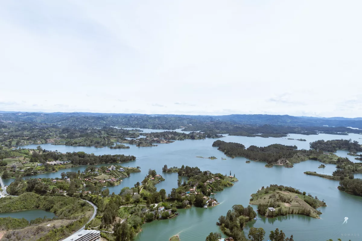 Panorama-Blick vom Piedra del Peñol in Guatapé, Kolumbien, auf den türkisblauen Stausee mit grünen Inseln und Hügeln im Hintergrund