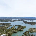 Panorama-Blick vom Piedra del Peñol in Guatapé, Kolumbien, auf den türkisblauen Stausee mit grünen Inseln und Hügeln im Hintergrund